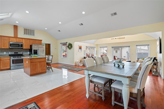 dining area with light hardwood / wood-style floors and lofted ceiling