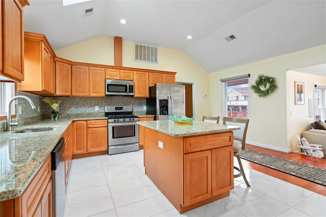 kitchen featuring sink, appliances with stainless steel finishes, lofted ceiling, and a center island