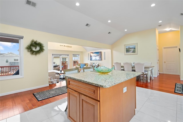 kitchen featuring lofted ceiling, a center island, and light stone counters