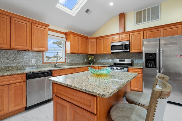 kitchen featuring sink, a center island, lofted ceiling with skylight, a breakfast bar, and appliances with stainless steel finishes