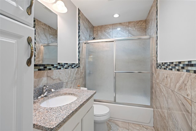 full bathroom featuring tile walls, toilet, vanity, and combined bath / shower with glass door