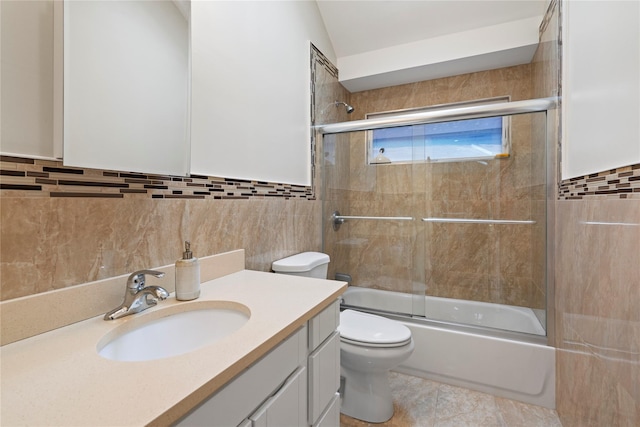 full bathroom with toilet, shower / bath combination with glass door, tile walls, tile patterned floors, and vanity