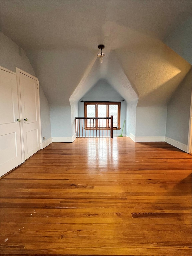 bonus room with vaulted ceiling and wood-type flooring