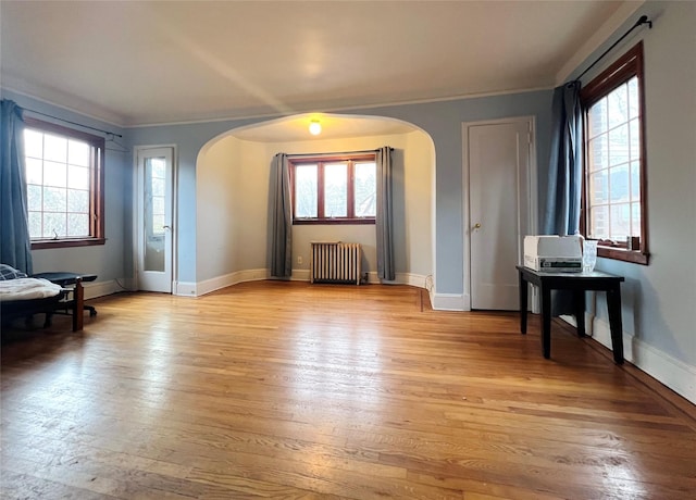 interior space with radiator, ornamental molding, and light hardwood / wood-style floors