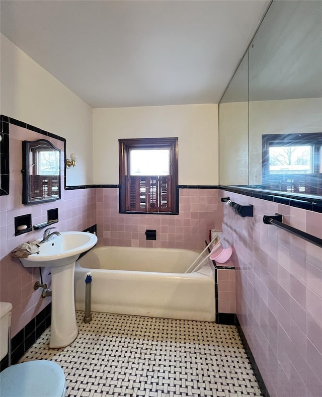 bathroom with tile walls, a bathtub, and tile patterned flooring