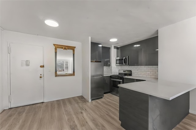 kitchen featuring stainless steel appliances, light hardwood / wood-style flooring, decorative backsplash, and kitchen peninsula