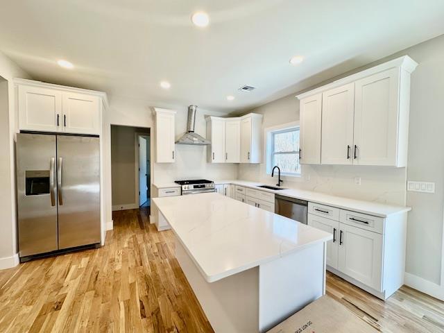 kitchen with white cabinetry, sink, wall chimney exhaust hood, and appliances with stainless steel finishes