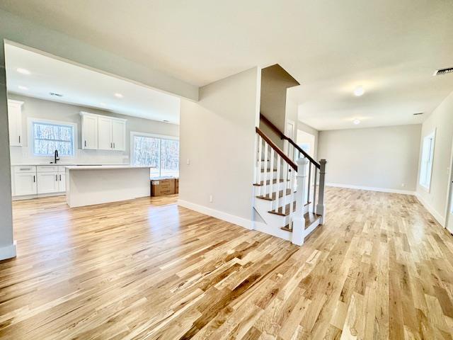 unfurnished living room featuring light wood-type flooring and sink