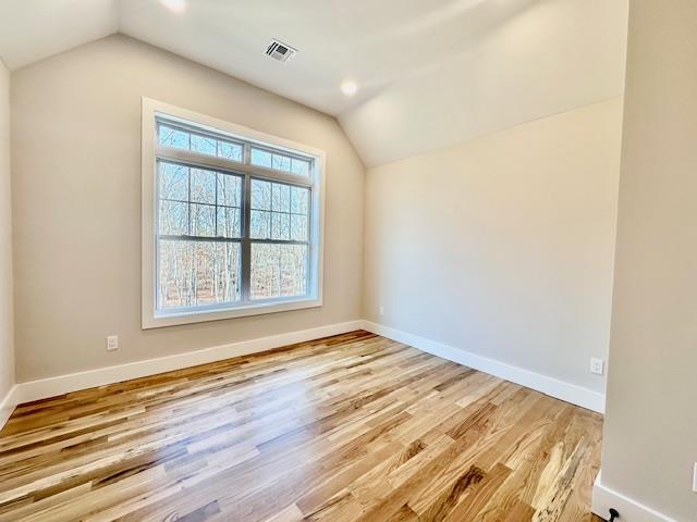 additional living space with light hardwood / wood-style floors and vaulted ceiling