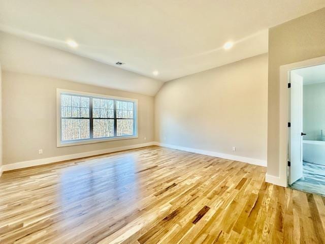 unfurnished room with light wood-type flooring and vaulted ceiling