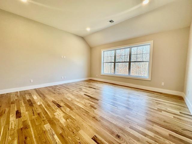 spare room featuring light hardwood / wood-style floors and lofted ceiling