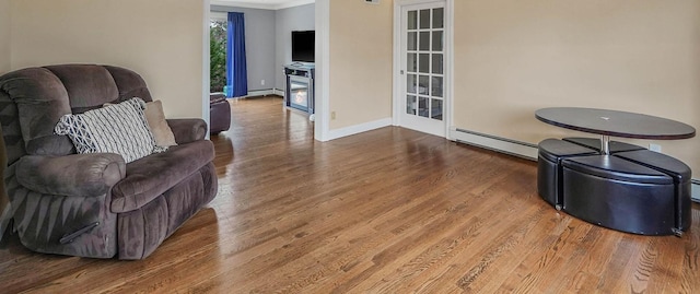 living room with wood-type flooring, a baseboard radiator, and ornamental molding