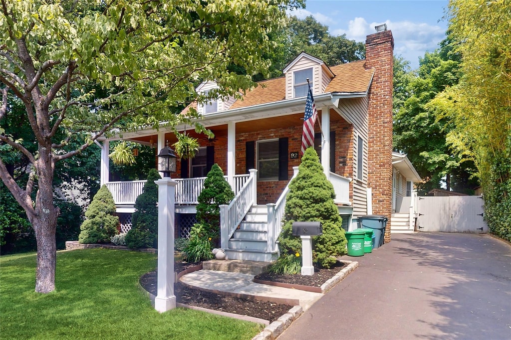 view of front of property featuring covered porch and a front lawn