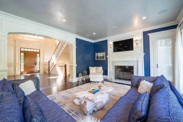 living room with hardwood / wood-style flooring, decorative columns, ornamental molding, and a fireplace