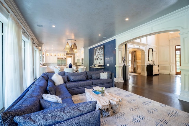 living room featuring wood-type flooring, ornamental molding, and decorative columns