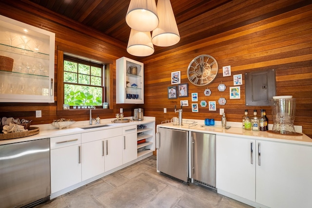 kitchen featuring built in fridge, sink, white cabinets, and wood walls