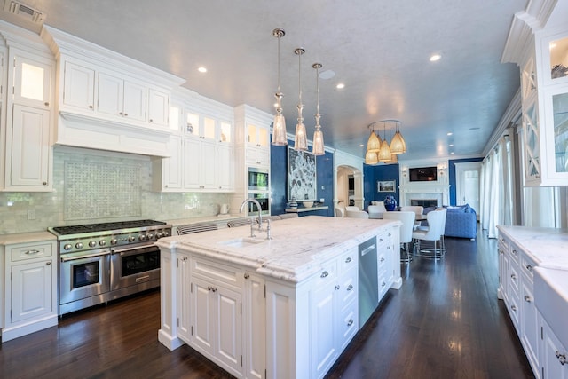 kitchen with hanging light fixtures, white cabinets, sink, and stainless steel appliances