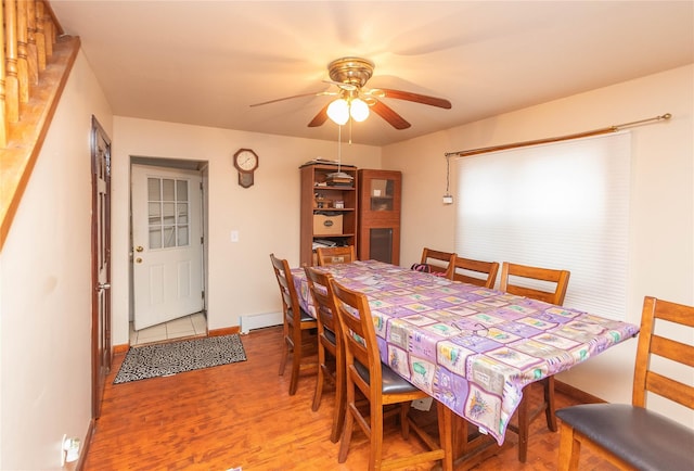 dining room featuring a baseboard heating unit, ceiling fan, and wood-type flooring