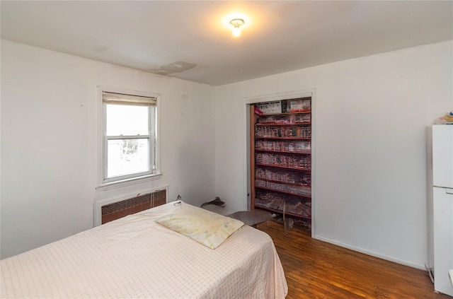 bedroom with radiator, white refrigerator, and dark hardwood / wood-style floors