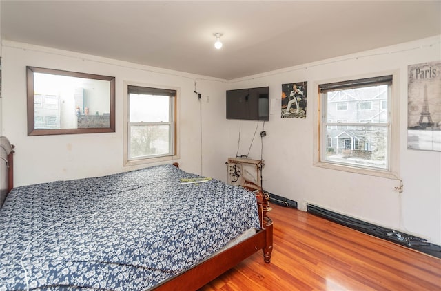 bedroom featuring hardwood / wood-style flooring, multiple windows, and crown molding