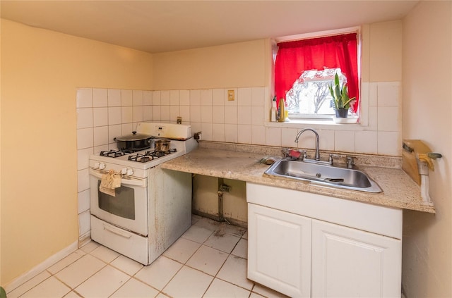 kitchen with tasteful backsplash, sink, white cabinetry, white range with gas stovetop, and light tile patterned floors