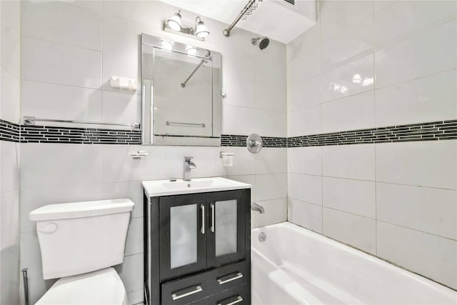 full bathroom featuring toilet, tiled shower / bath combo, tile walls, and vanity