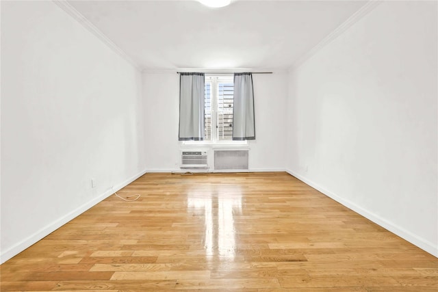 spare room featuring light wood-type flooring, a wall unit AC, and ornamental molding