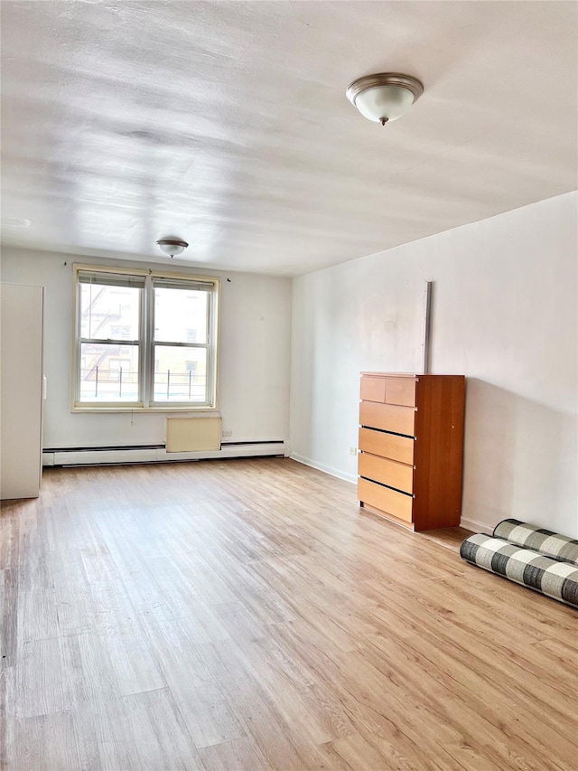 empty room with light wood-type flooring and a baseboard radiator