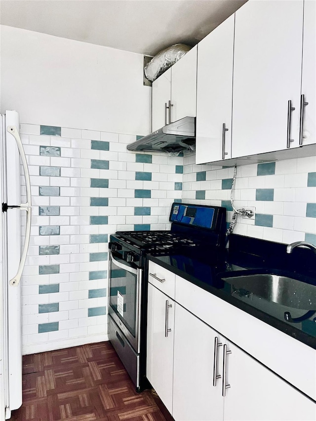 kitchen featuring sink, tasteful backsplash, stainless steel range with gas cooktop, white cabinetry, and white fridge