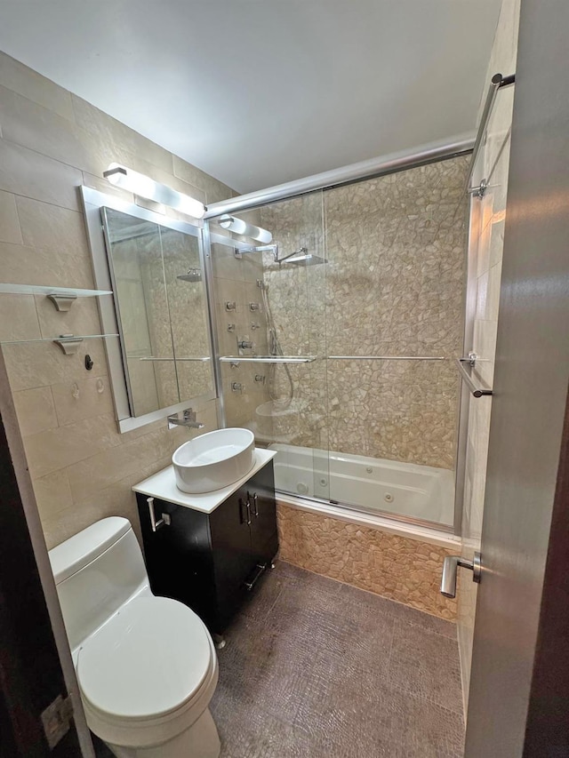 full bathroom with vanity, toilet, tiled shower / bath, and tile walls