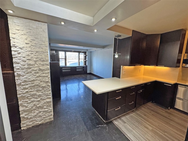 kitchen with dark hardwood / wood-style floors, built in desk, backsplash, kitchen peninsula, and dark brown cabinets