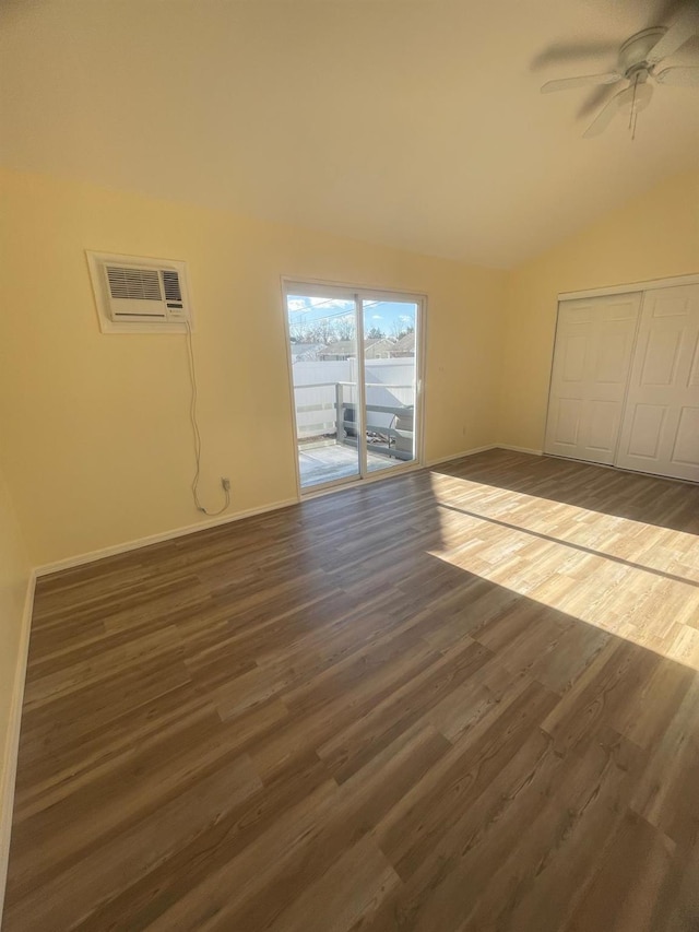 interior space with dark hardwood / wood-style floors, vaulted ceiling, ceiling fan, and an AC wall unit