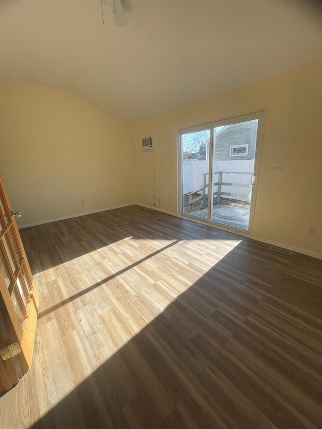 spare room with dark hardwood / wood-style floors, a wall mounted AC, and lofted ceiling