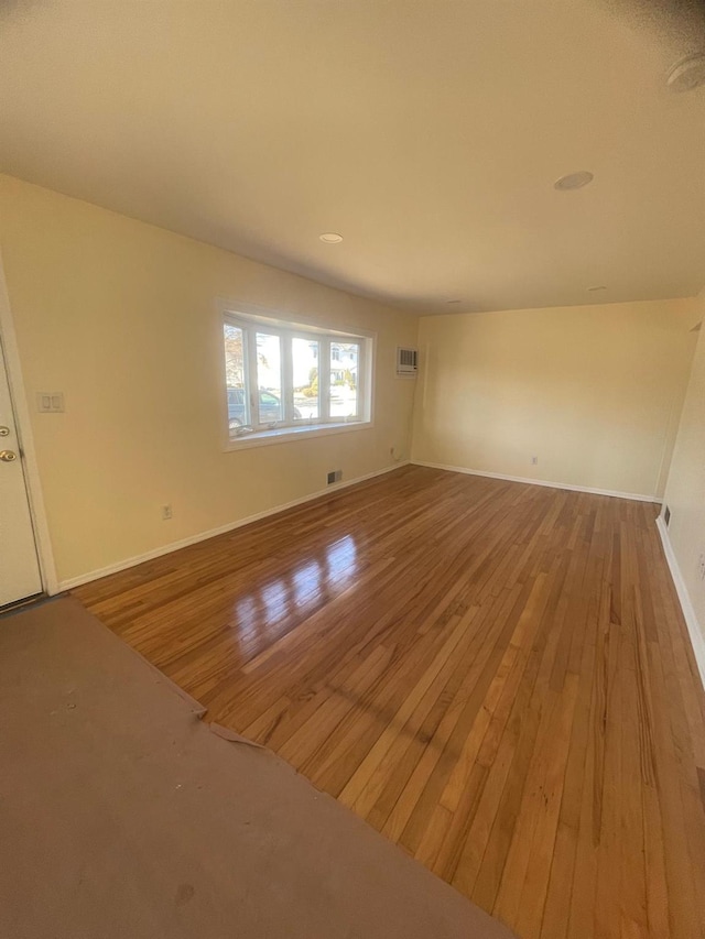 empty room with a wall mounted AC and wood-type flooring