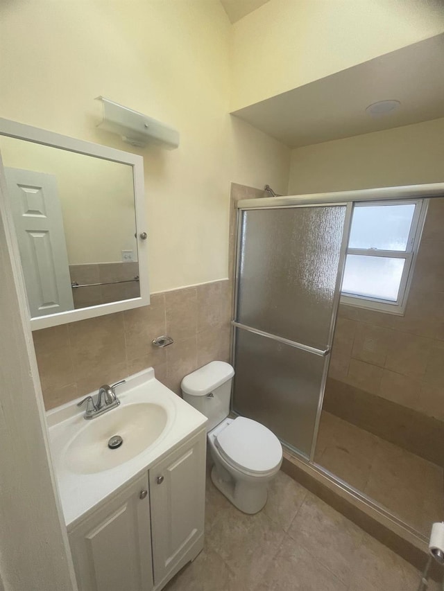 bathroom with vanity, a shower with door, toilet, and tile walls