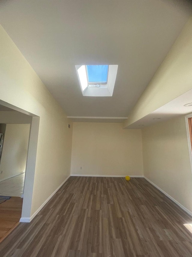 interior space with vaulted ceiling with skylight and dark hardwood / wood-style flooring