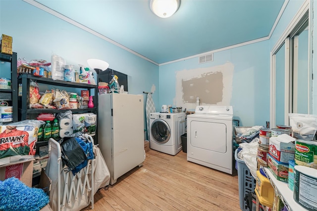 washroom with light hardwood / wood-style floors, washing machine and dryer, and crown molding