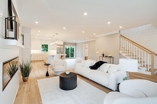 living room with a chandelier, light hardwood / wood-style flooring, and ornamental molding