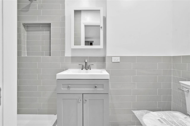 bathroom with vanity, a shower, and tile walls