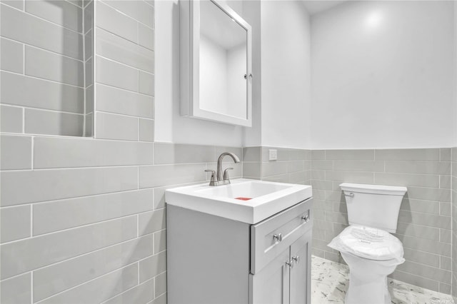 bathroom featuring vanity, toilet, and tile walls