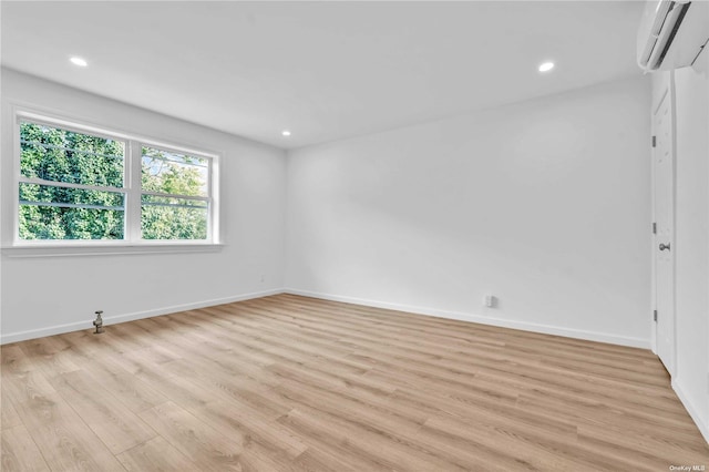 spare room featuring light wood-type flooring and a wall mounted AC