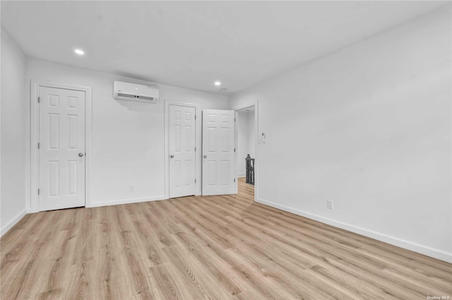 unfurnished bedroom featuring light hardwood / wood-style floors and a wall mounted air conditioner