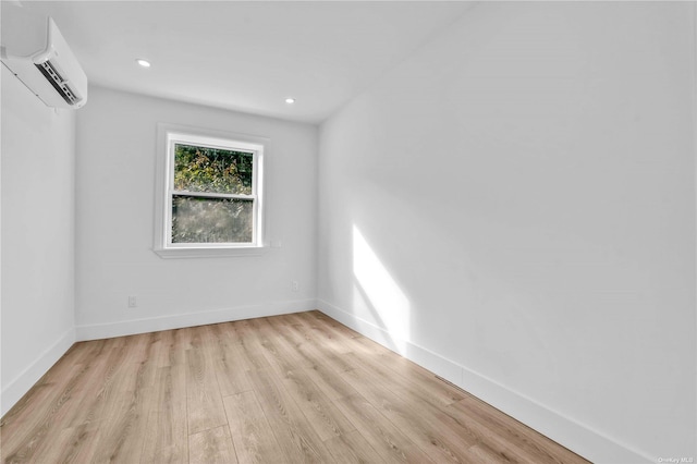 unfurnished room with an AC wall unit and light wood-type flooring