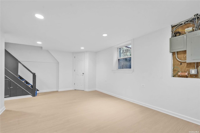 basement featuring light wood-type flooring and electric panel