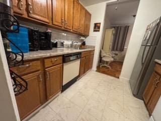 kitchen featuring white dishwasher, brown cabinetry, and light countertops