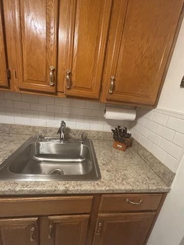 kitchen featuring a sink, decorative backsplash, brown cabinetry, and light countertops