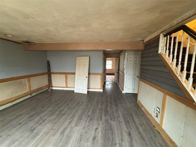 spare room featuring dark hardwood / wood-style flooring, a textured ceiling, and wooden walls