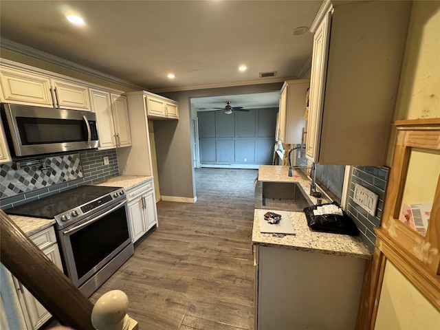 kitchen with ceiling fan, ornamental molding, light stone counters, appliances with stainless steel finishes, and dark hardwood / wood-style flooring