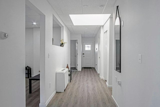 hallway with light hardwood / wood-style flooring and a paneled ceiling