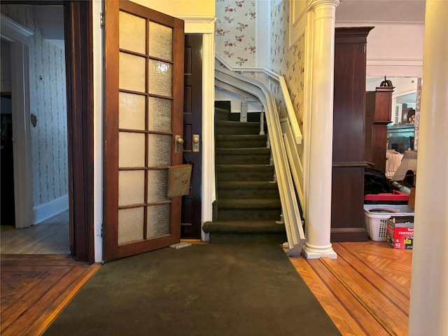 stairs featuring wallpapered walls and ornate columns